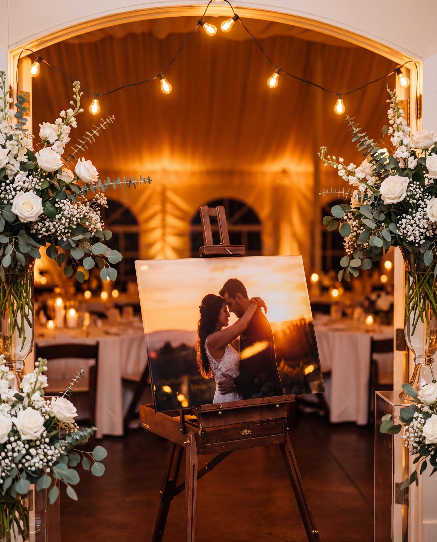 Acrylic couple photo panel displayed on an easel at a wedding reception entrance with floral arrangements