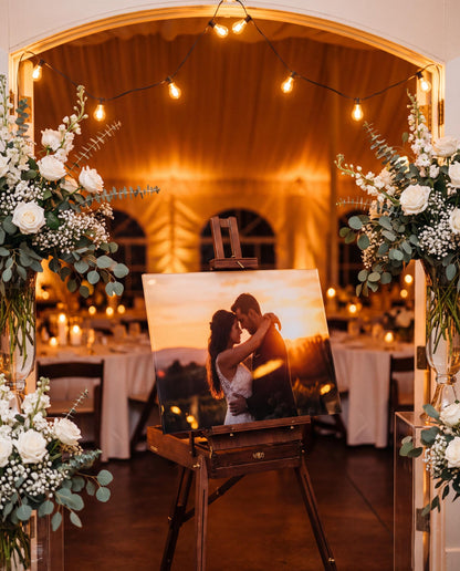 Acrylic couple photo panel displayed on an easel at a wedding reception entrance with floral arrangements