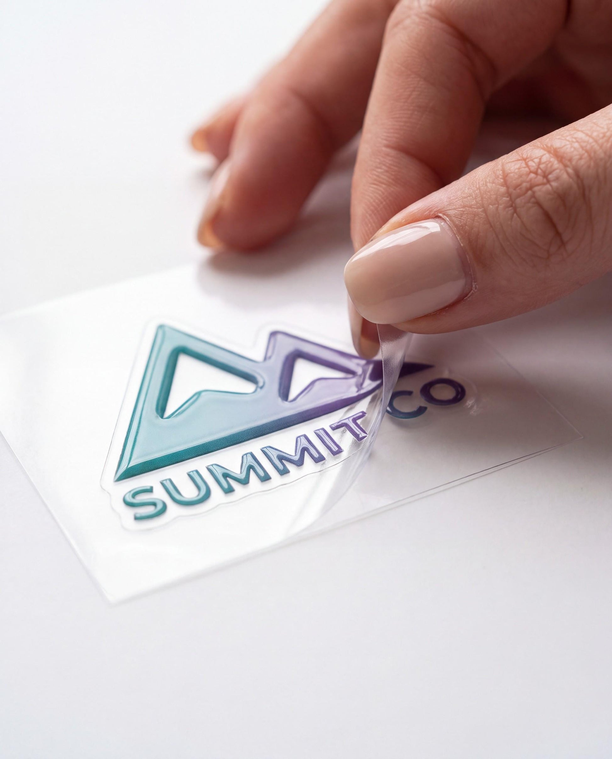 Hand peeling a glossy raised dimensional custom logo sticker off its clear transfer film
