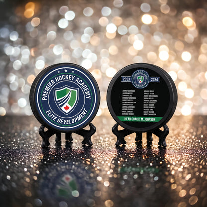 Custom hockey puck with engraved team crest and Premier Hockey Academy Elite Development logo, standing upright on sparkly bokeh background