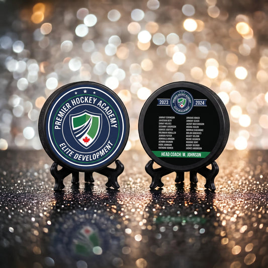 Custom hockey puck with engraved team crest and Premier Hockey Academy Elite Development logo, standing upright on sparkly bokeh background