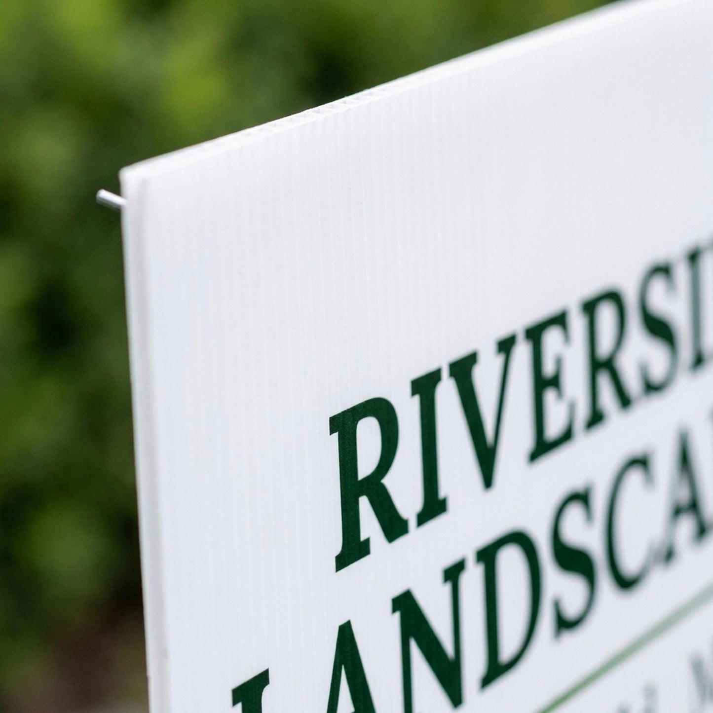 Close-up of custom yard sign corner showing printed green text and corrugated plastic texture