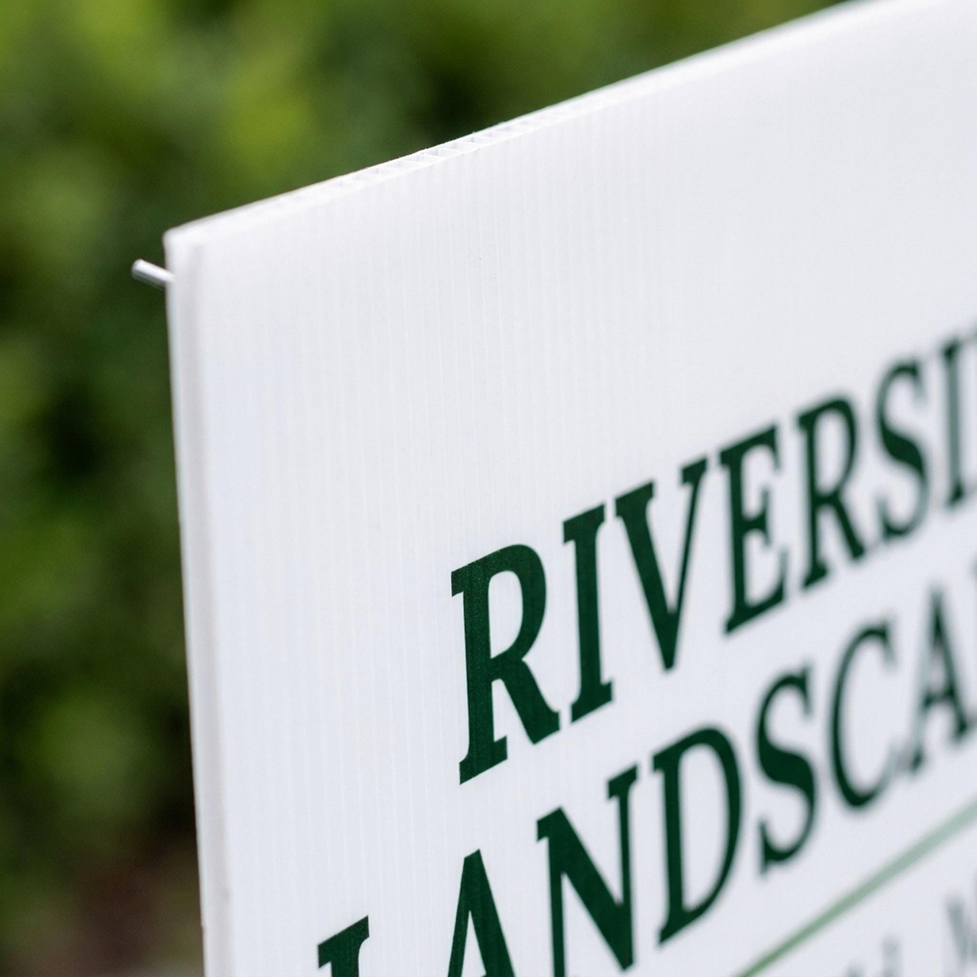 Close-up of custom yard sign corner showing printed green text and corrugated plastic texture