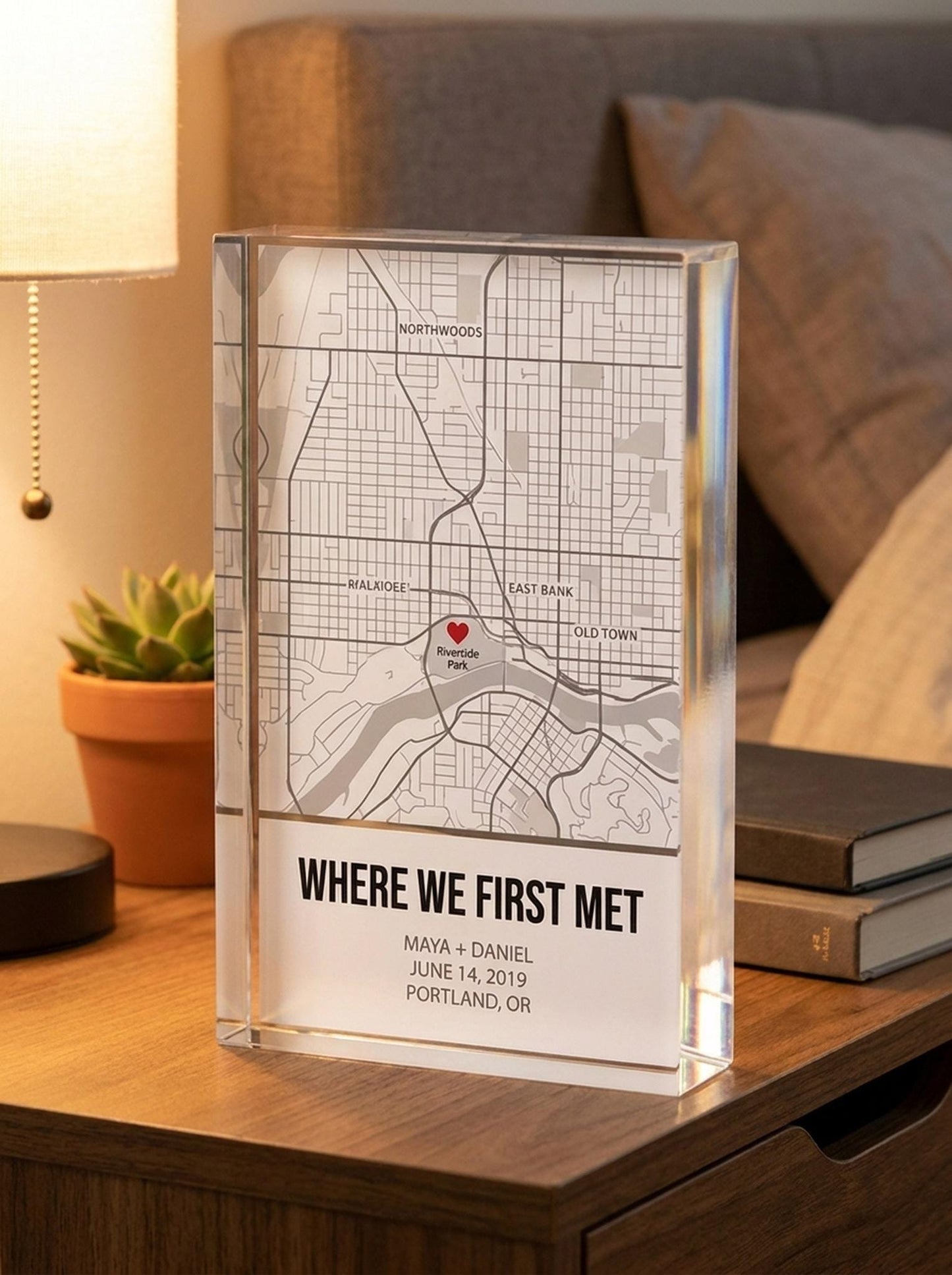 Personalized map acrylic block displayed on a wooden nightstand with lamp and books