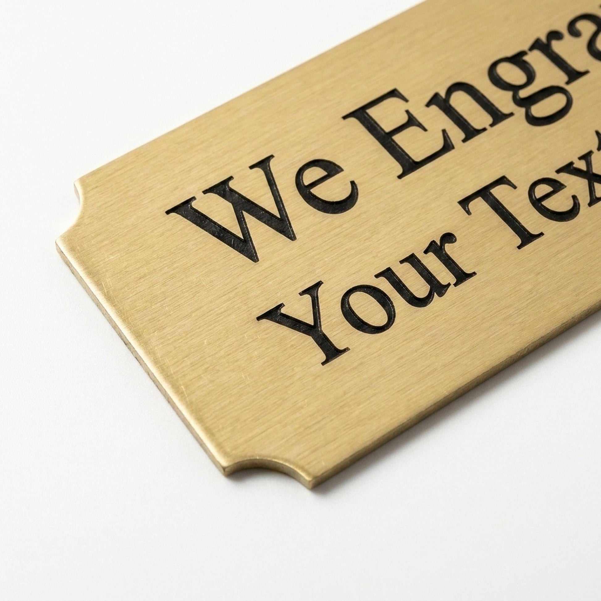 Close-up of engraved brass nameplate corner showing brushed metal texture and cut edge detail