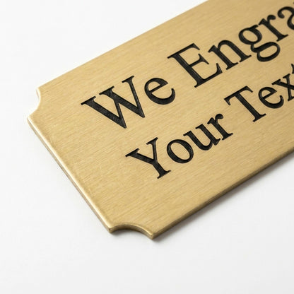 Close-up of engraved brass nameplate corner showing brushed metal texture and cut edge detail