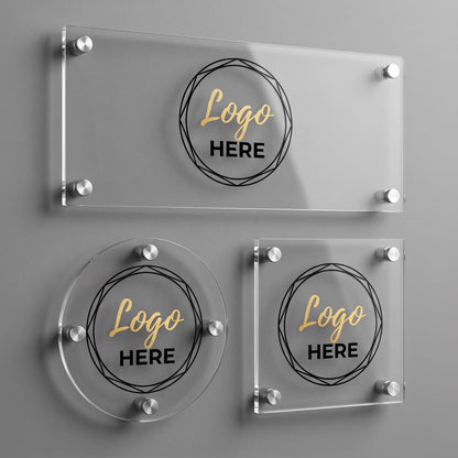 Three custom acrylic business logo plaque shapes, rectangle, circle, and square, with silver standoff mounts on a gray wall