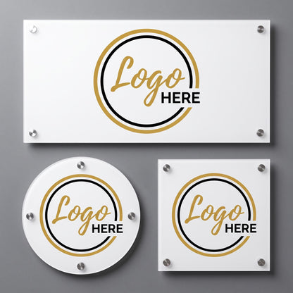 Three white acrylic logo plaques with gold and black circular emblem design and standoff mounts on a gray wall