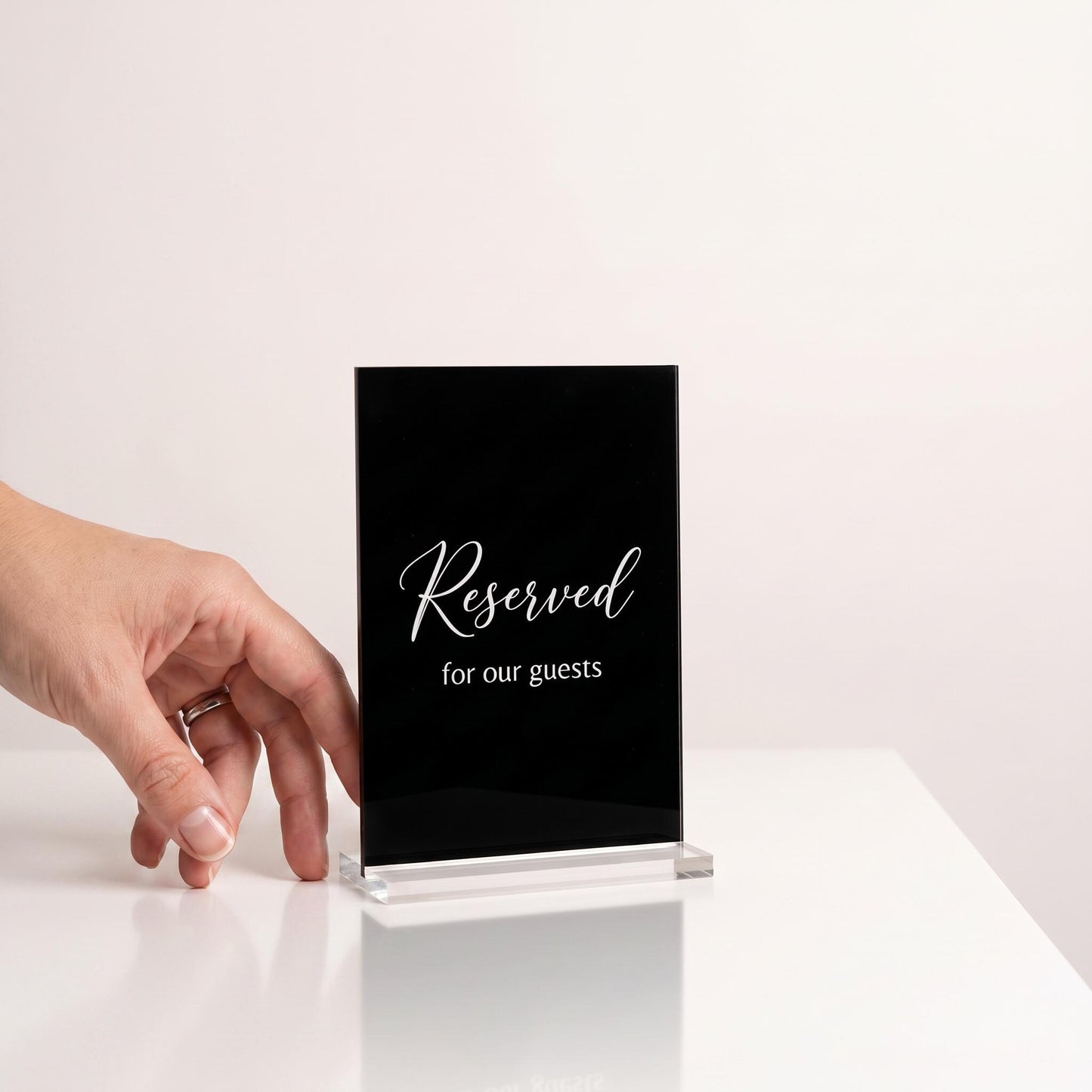 Custom acrylic table sign next to a hand to show its compact tabletop size.