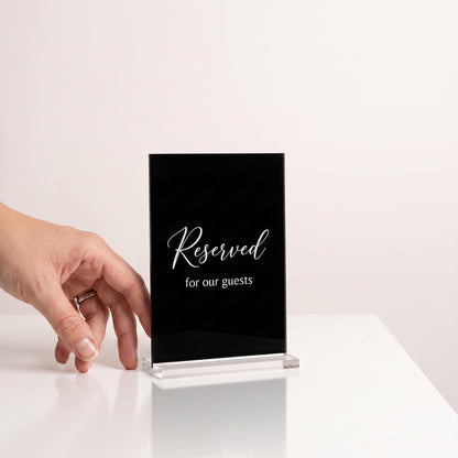 Custom acrylic table sign next to a hand to show its compact tabletop size.