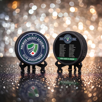 Front and back of custom hockey puck showing crest logo on front and engraved player roster with coach name on back
