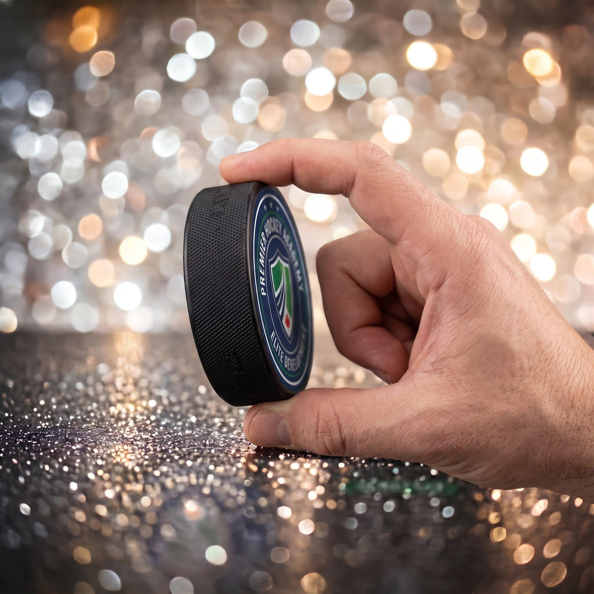 Custom hockey puck held between two fingers showing compact size on sparkly background
