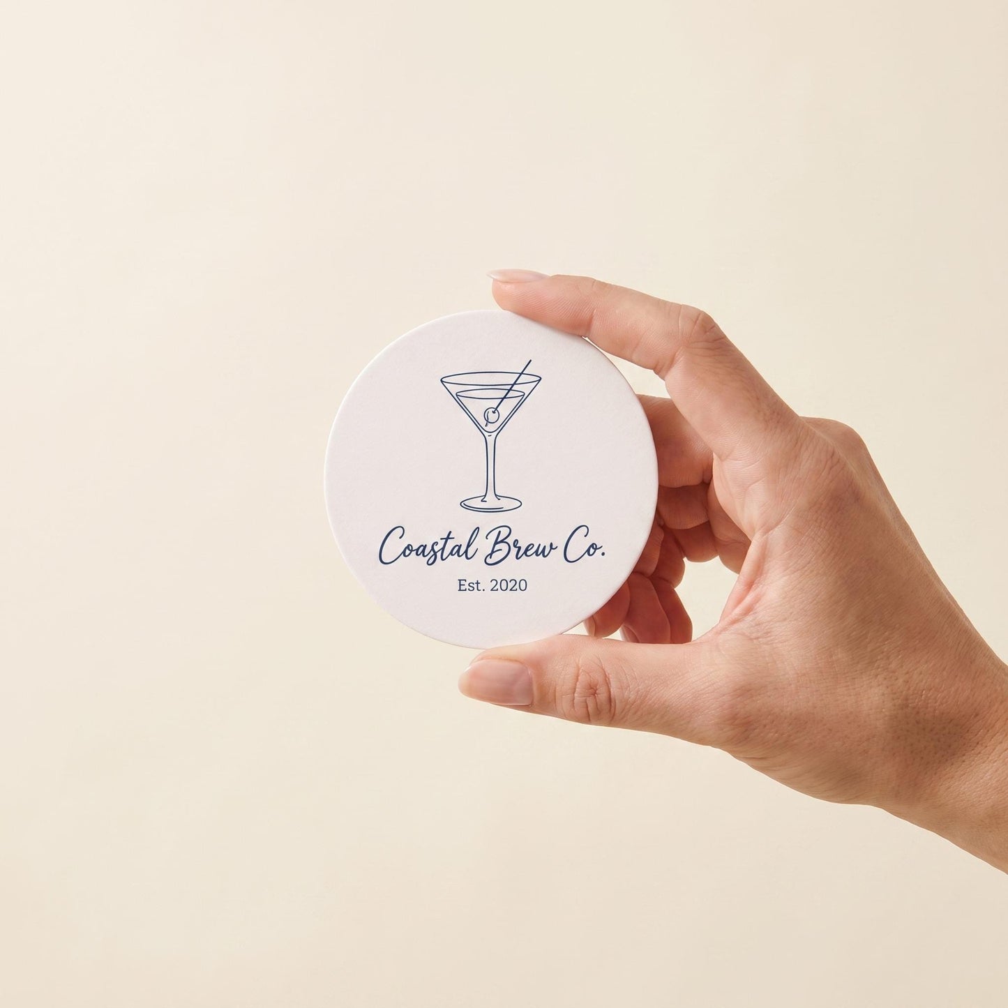 A custom logo coaster held between two fingers to show its compact drink coaster size.