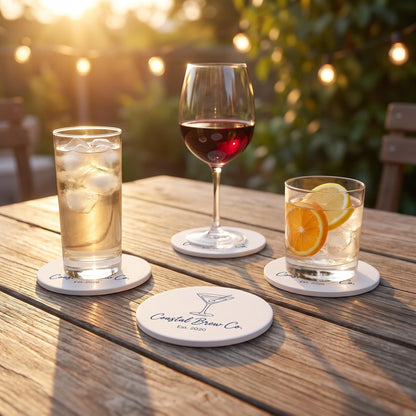 Custom branded coasters in use on an outdoor patio table under various drink glasses at golden hour.