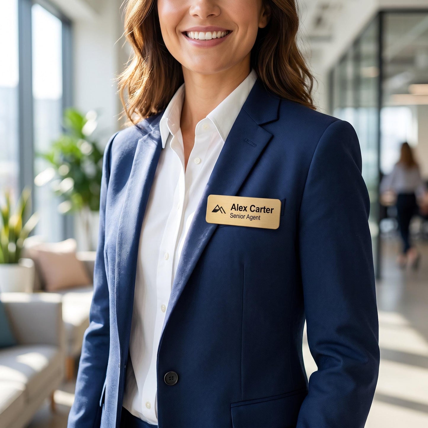 Professional wearing a navy blazer with the custom brushed-gold name badge pinned to the lapel in an office setting.