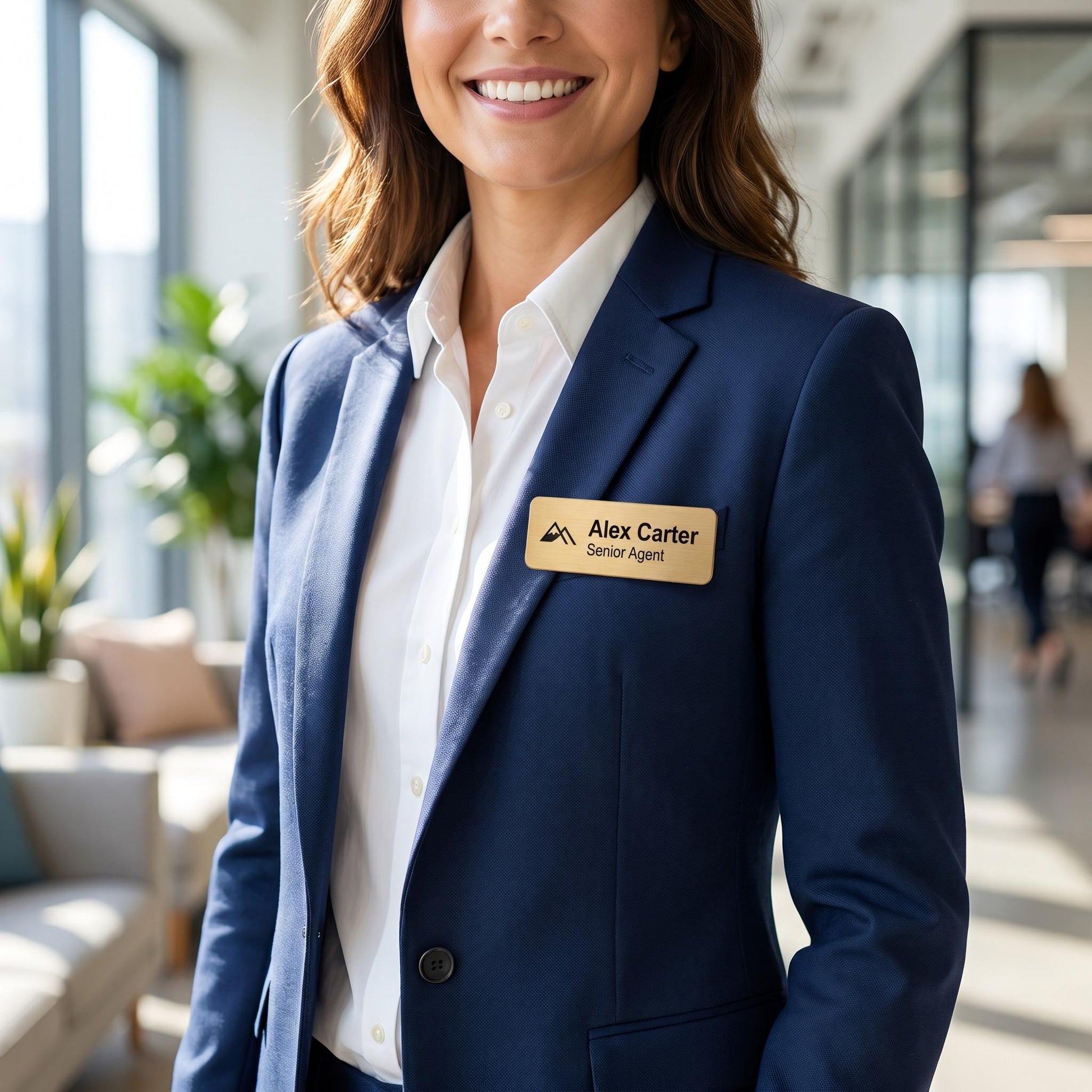 Professional wearing a navy blazer with the custom brushed-gold name badge pinned to the lapel in an office setting.