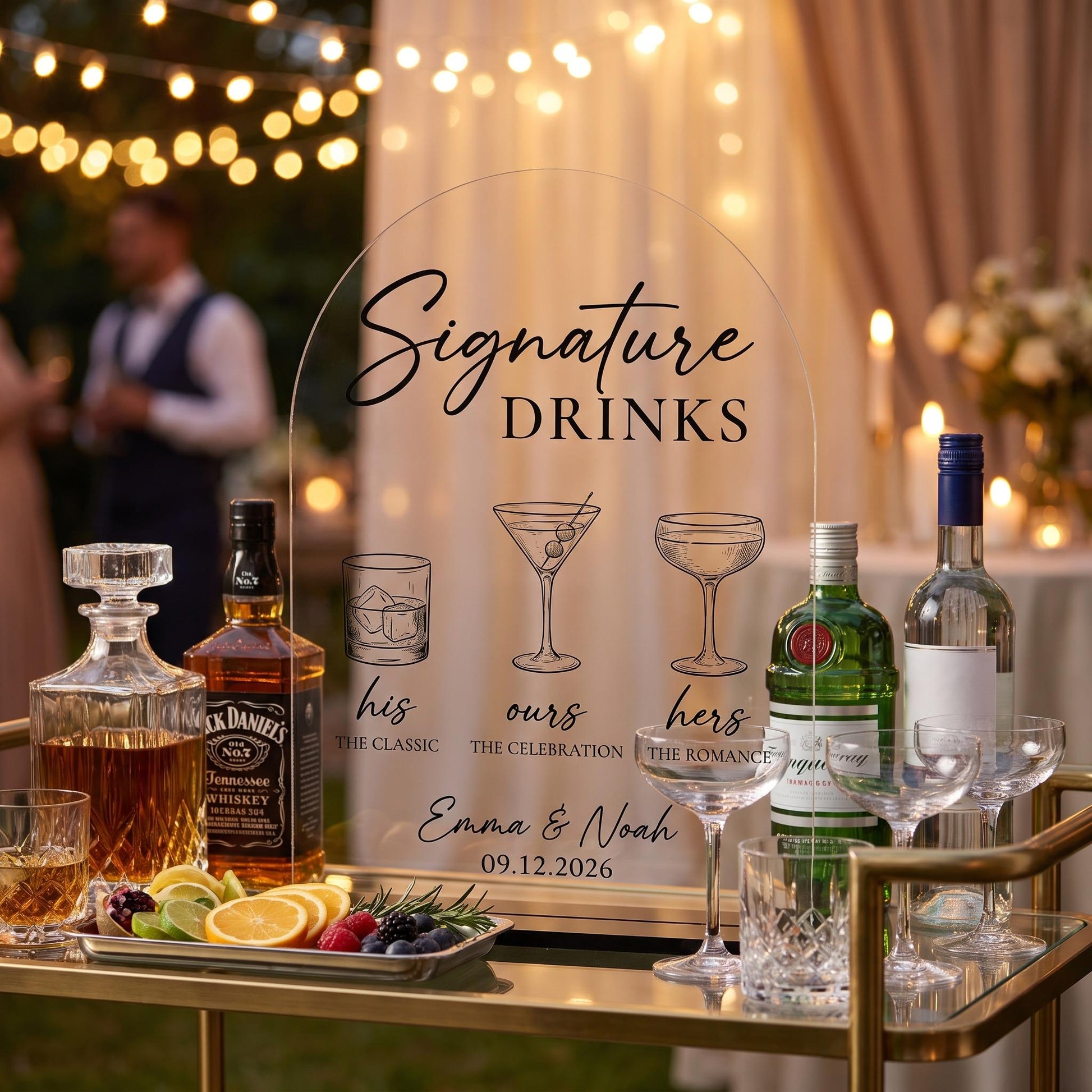 Custom acrylic signature drinks sign displayed on a bar cart at an evening celebration surrounded by glassware and string lights.