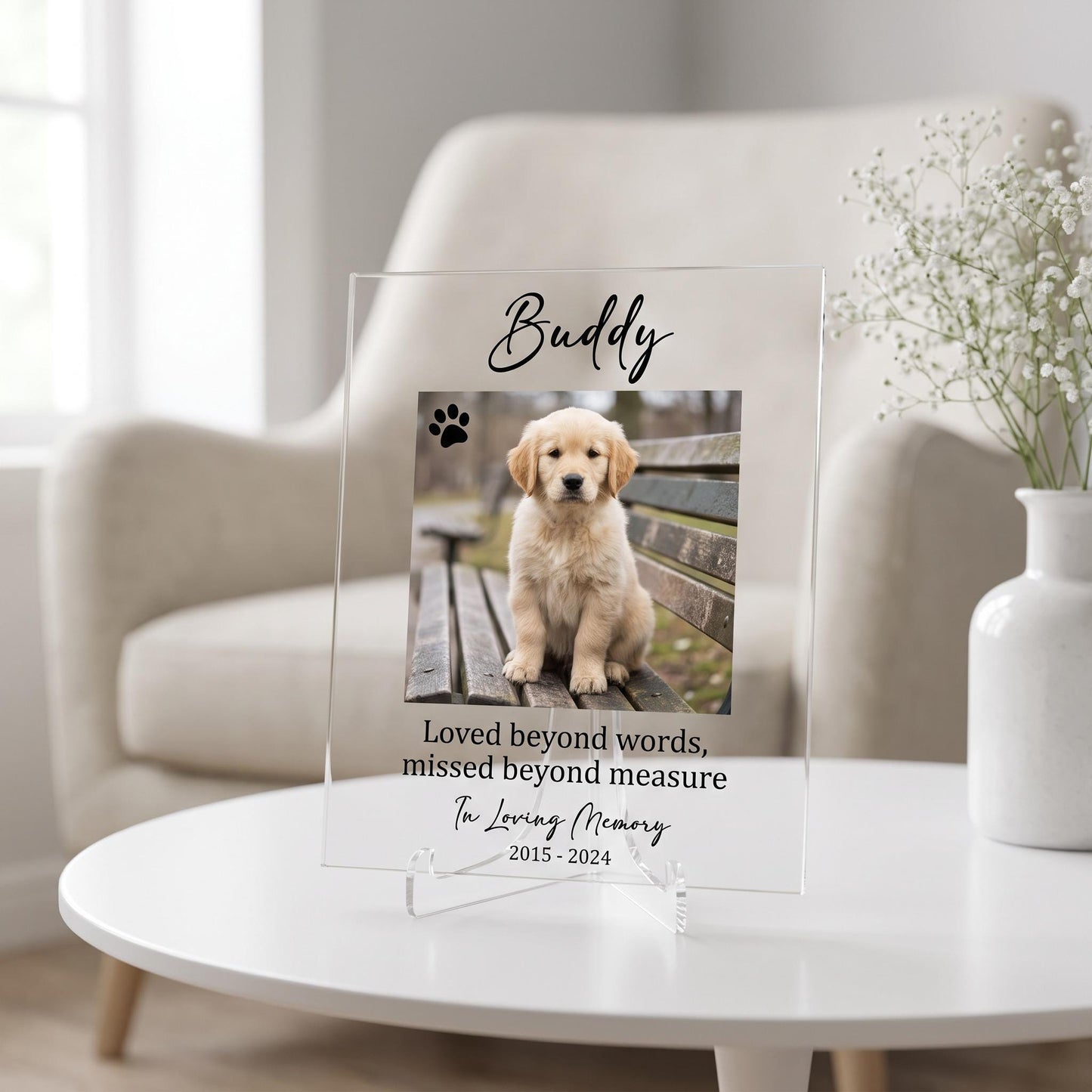 Clear acrylic pet memorial plaque with a printed puppy photo, pet name, memorial verse, and dates, displayed on a stand on a white table.